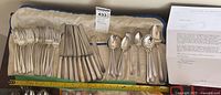 Overall view: six dinner forks, six dinner knives, six tablespoons, six teaspoons arranged in roll, ruler showing sizes, letter alongside.
