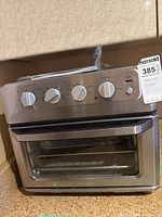 Front view of stainless steel Chefman air fryer toaster oven showing control knobs, glass door, and MaxSold tag.