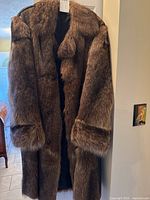 Full front view of brown fur coat on hanger