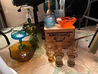 Full view of art glass collection on floor featuring vases, bowls, ashtray, and glasses.