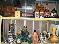 Shelf with various ceramic and stoneware bottles, beer steins, and decorative wooden boxes