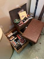 Boxes and a vintage suitcase with various audio cassettes and CDs visible inside.