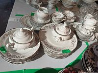 Walbrazyck china plates, teacups, saucers, sugar bowls stacked on a table with green price tags visible.