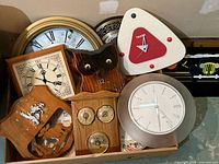 Photo showing a group of clocks including owl-shaped, triangular Talking clock, gold round clock and others.