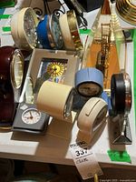 Collection of various vintage desk, alarm, and travel clocks showing multiple styles, colors, and sizes from 3.5 to 9 inches.