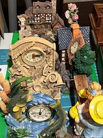 Photo of decorative clocks including fish figurine and small house models.