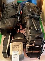 Photo showing two large black boom boxes stacked, featuring cassette decks, control buttons, and carrying handles.