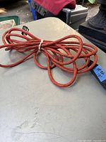 Photo of red extension cord coiled on a table showing its length and condition.