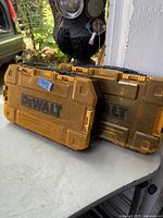 Two yellow Dewalt storage boxes placed on a grey surface, showing their front side with Dewalt logo and latches.