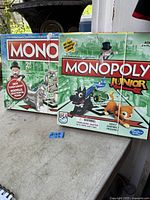Photo of two Monopoly board games including Monopoly and Monopoly Junior side by side showing front boxes.