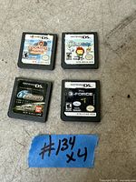 Photo showing four Nintendo DS game cartridges on a concrete surface with a blue tape labeled '#134 x4'.