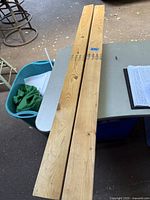 Four pieces of wooden 2x4 lumber on a table with visible grain and knots, showing length and surface detail.