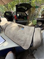 Beige Quest brand tent bag with carry handle and wheels visible, showing exterior condition and branding.