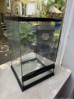 Full view of glass reptile cage showing clear glass panels and black framing.