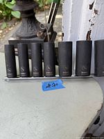 Photo of eight black DeWalt impact sockets arranged on a metal rail, showing varying sizes and DeWalt branding with part numbers.