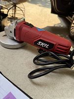 Side view of the Skil angle grinder showing the brand logo and power cord.