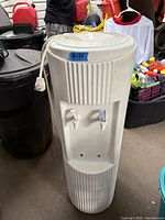 Photo of white water cooler with hot and cold water taps and power cord showing normal wear