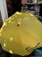 Opened yellow beach umbrella showing canopy with printed text 'beach umbrella' and 'no name'.