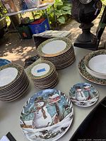 Stack of Christmas themed dinner plates, bread plates, and soup bowls with gold accents