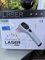 Photo of the unopened retail box showing the handheld laser device image and branding.