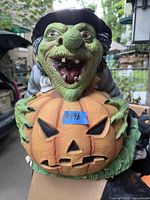 Close-up of detailed Halloween witch figure holding a pumpkin with carved face