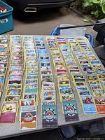 Image showing many Pokémon trading cards spread out on a table, organized in rows with a blue background visible at the bottom.