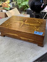Closed view of the wooden jewelry box showing star inlaid pattern on lid and wood grain.