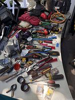 Photo showing assorted hand tools like pliers, screwdrivers, rope, filters, and clamps on the table.