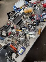 Wide view of the assorted tools and hardware spread on a table showing sockets, clamps, hand tools, and small parts.