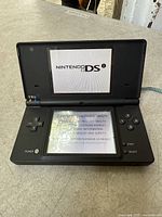 Front view of the Nintendo DS console powered on, showing Nintendo DS startup screen on both displays.