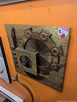 Square metal wall art with detailed layered geometric and circular design in bronze and gold tones