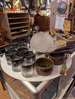 Photo showing glassware including nine etched glasses, two ceramic bowls, fiber optic lamp and additional miscellaneous items on a round white table.