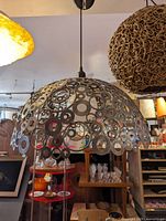 Industrial metal pendant light hanging from ceiling, featuring a dome-shaped shade made of various sized circular metal rings.