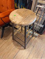 Photo showing industrial style stool with round wooden top and metal base on a wooden floor.