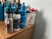 All five bottles lined on dresser showing materials, colors and graphics