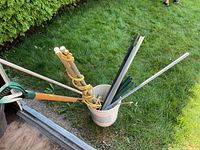 Bucket with assorted poles, stakes and handles next to shed threshold