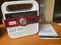 Front view of Eton Solarlink FR370 radio showing controls, speaker, American Red Cross logo, and included manual