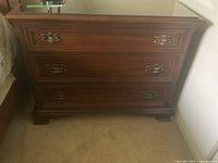 Front view of dresser showing three drawers and brass hardware