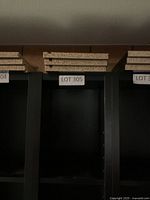 Front upper section of black IKEA media tower showing adjustable shelf holes and stack of extra shelves on top