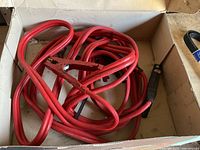 Box containing coiled red jumper cables with clamps visible
