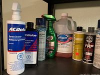 Shelf with AC Delco cleaner, Cleanawax, CarBrite aerosol, Turtle Wax spray, other bottles