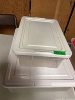 Two plastic storage totes stacked, showing lids and condition