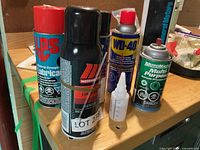 Group of aerosol lubricant cans and squeeze bottle on workbench