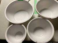 Four nested white plastic mixing bowls showing all sizes