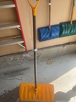 Full view of yellow Garant snow pusher standing upright