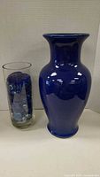 Photo showing the large blue ceramic vase and the tall clear glass vase filled with blue glass stones side by side for scale.