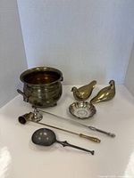 All items together including brass pot, brass birds, small dish with loonie, ladle, candle snuffer, and silver candle tool.