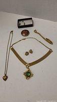 Overall lot of gold-tone costume jewelry items including necklaces, cloisonne brooch, earrings and cufflinks