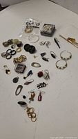 Top view of various costume rings and earrings arranged on a white surface