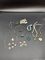 Overview of necklace, bracelet, earring, and pendant collection featuring turquoise and silver-tone jewelry on black background